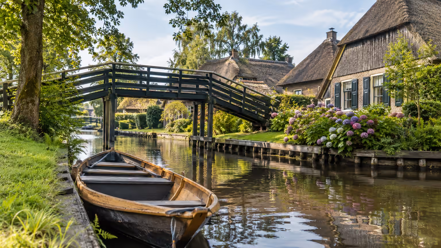 A view of a wooden boat at the edge of a Giethoorn canal beneath a small footbridge