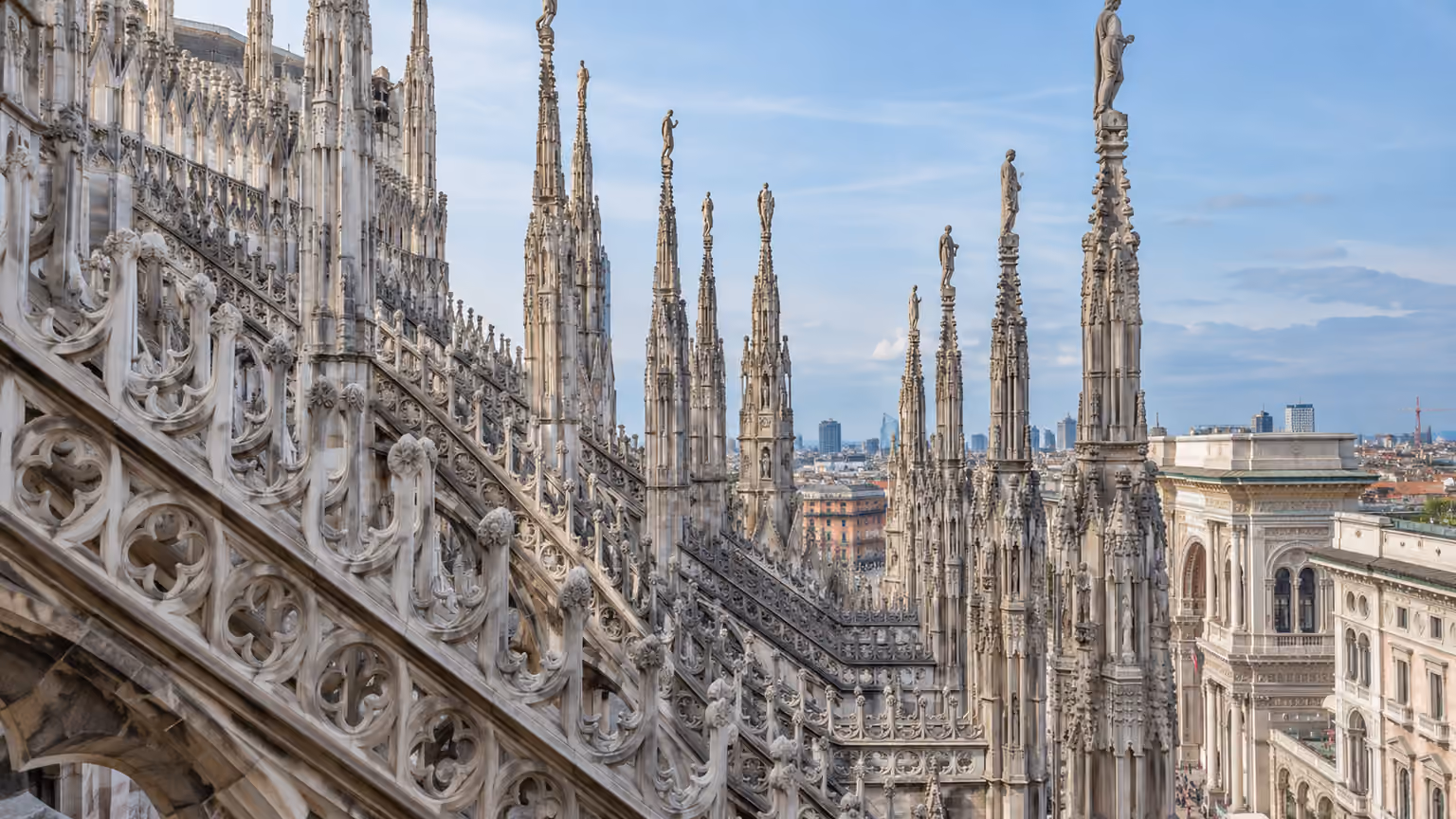 Close exterior view of ornate pale marble pinnacles and carved Gothic tracery on Milan