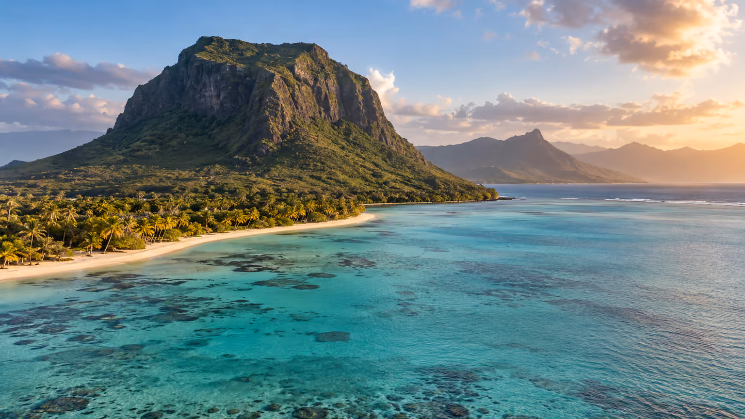 A rugged basalt mountain above a palm-lined beach and turquoise Indian Ocean lagoon
