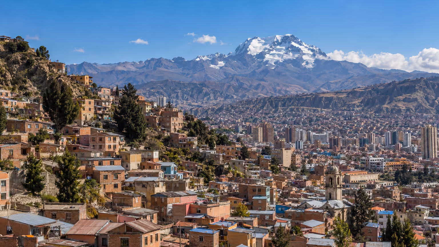 Brick houses on the slopes of La Paz beneath distant snow-covered Andean mountains