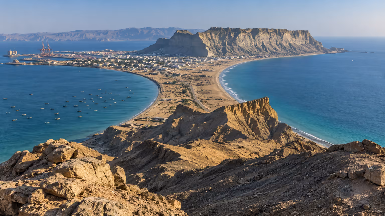 An arid rocky headland separating two curved bays beside the coastal city of Gwadar